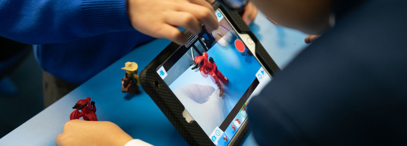 young boy taking photos of toys using a tablet