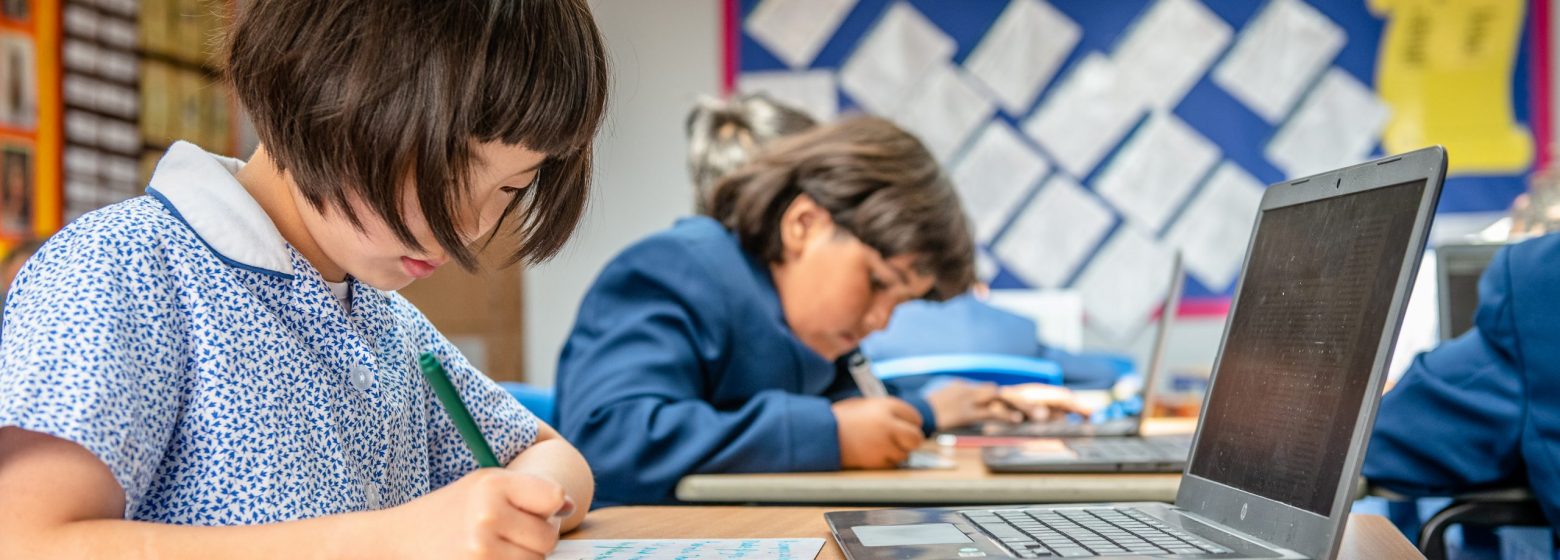 Students writing on a whiteboard while working on a laptop