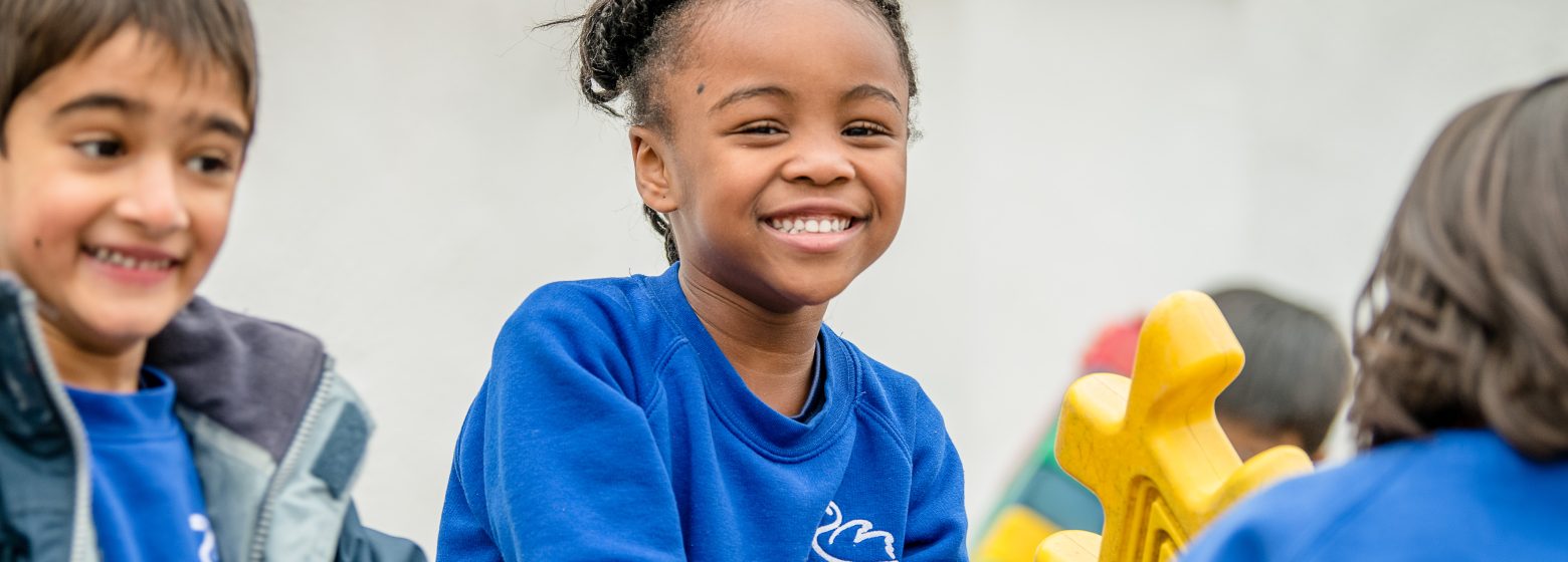 Young students smiling happily as they take part in outdoor play.