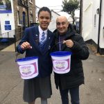 student holding a bucket of money