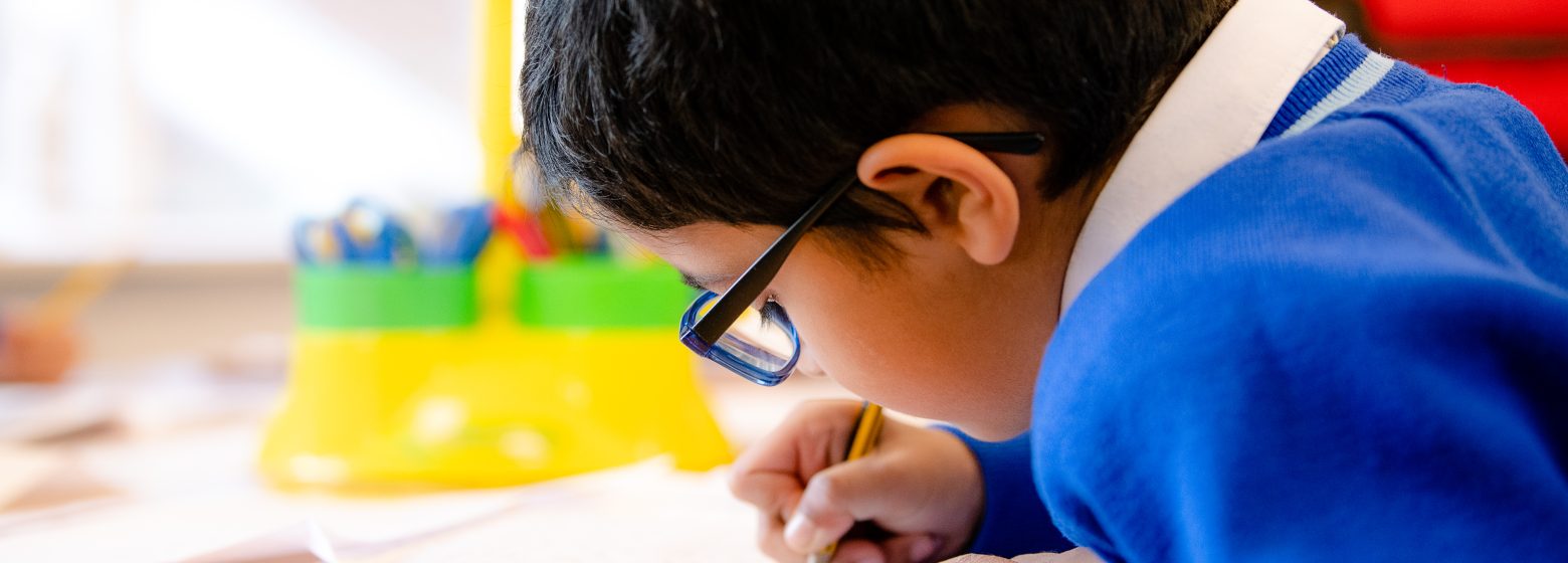 Boy writing out with pencil onto a piece of paper