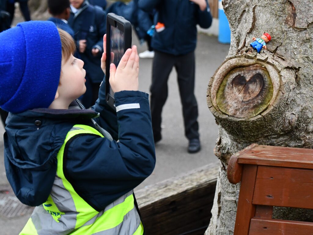 student taking a photo of a toy in a tree