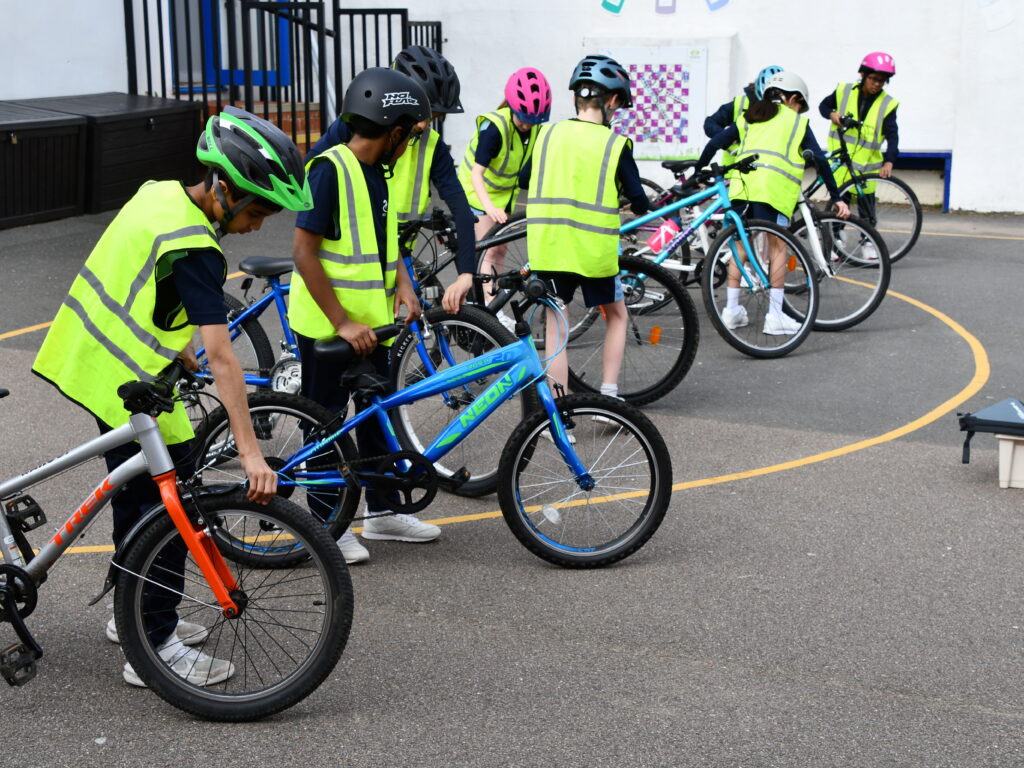group of children in hi-vis jackets holding their bikes