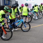 group of children in hi-vis jackets holding their bikes