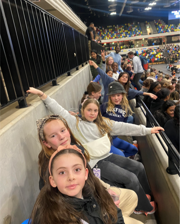 group of school students sitting in a row at a sporting event