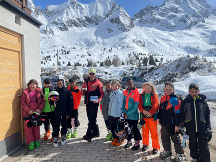 group of school students on a ski tree in front of a snowy mountain