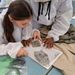 school students looking closely at a footprint