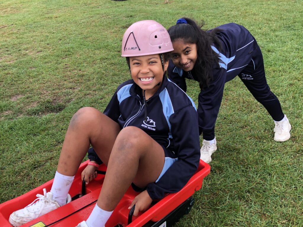student pushing her friend in a sledge