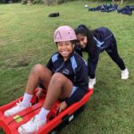student pushing her friend in a sledge
